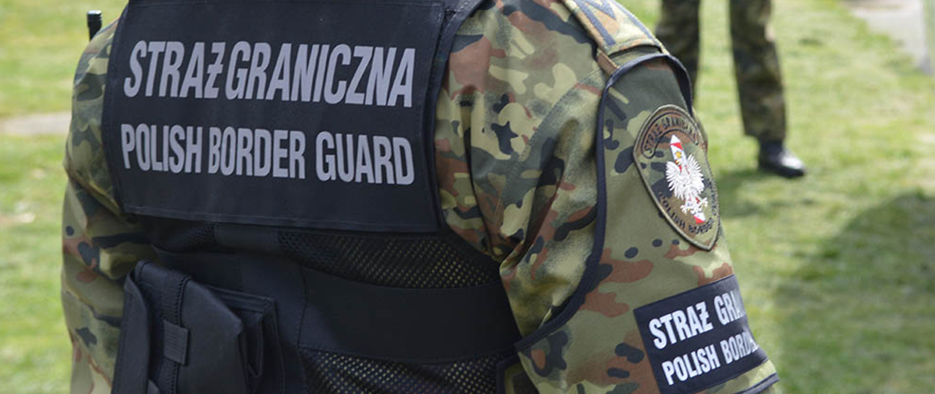 Funkcjonariusz Straży Granicznej stojący tyłem, na jego plecach napis "Straż Graniczna".