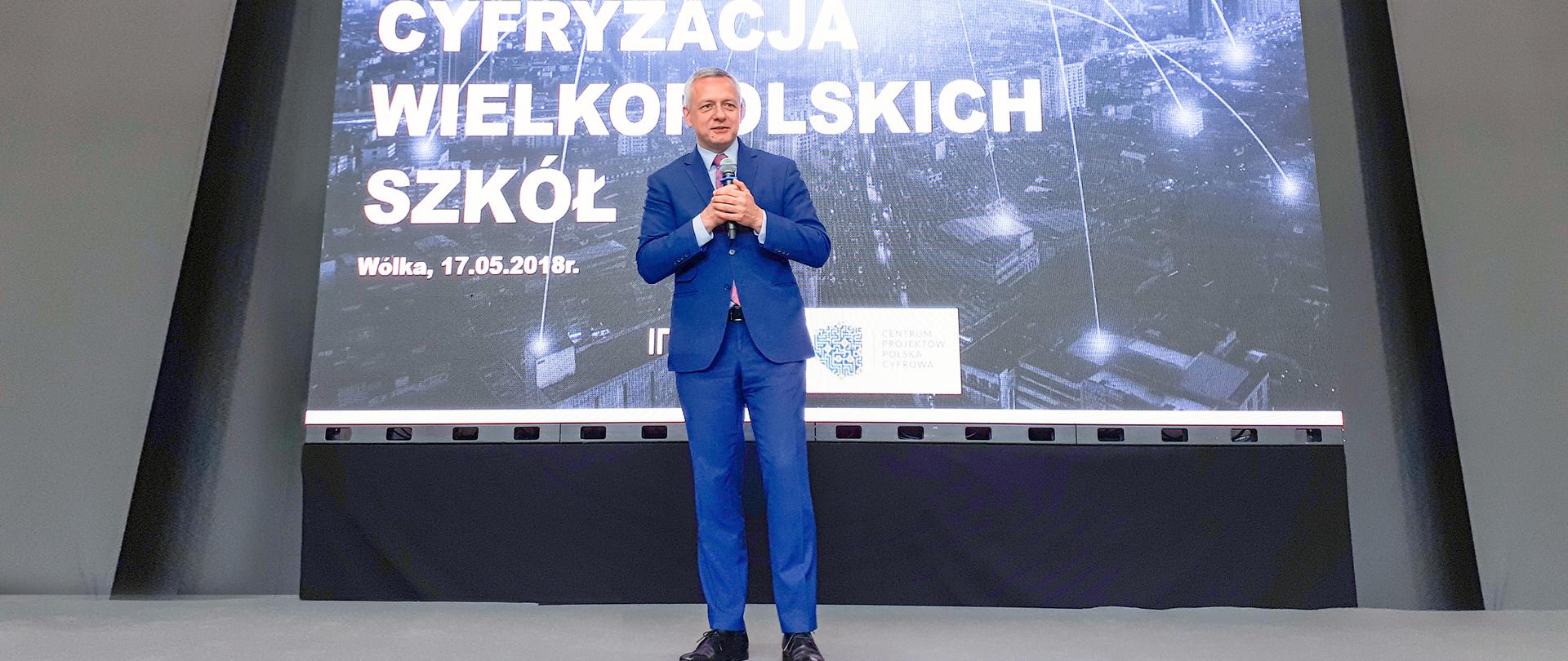 minister Marek Zagórski przemawia do publiczności. W tle prezentacja multimedialna
