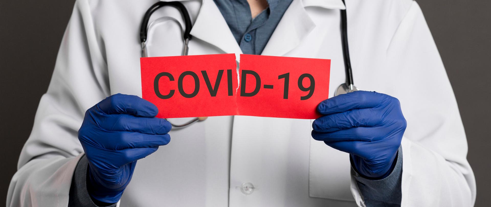 Doktor trzymający kartkę z napisem COVID-19