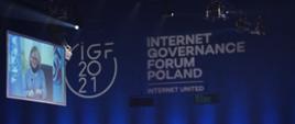 Szczyt Cyfrowy ONZ – IGF 2021. Publiczność – kadr z boku. Za nią logo IGF 2021. Po lewej stronie ekran, na którym wy świetlany jest rozmówca. Fot. PAP