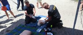 Na zdjęciu strażacy pokazują na fantomie szkoleniowym jak korzystać z defibrylatora AED