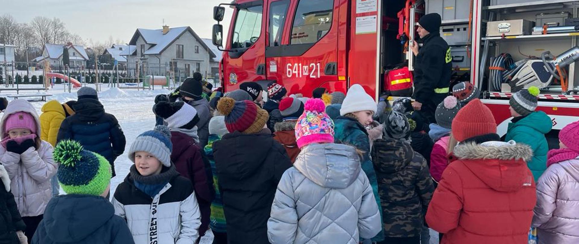 Wizyty w ramach akcji „Bezpieczne Ferie” 17.01.2024 r..- na zdjęciu dzieci oglądają sprzęt strażacki na powietrzu.