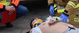 Strażak i ratownik medyczny udzielają pierwszej pomocy poszkodowanemu