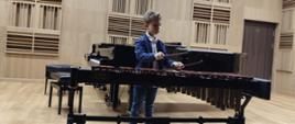 Na scenie Uczeń pierwszej klasy Mikołaj gra solo kolędę na ksylofonie.