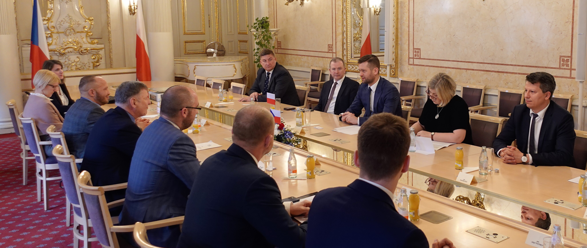 Zdjęcie przedstawia szeroki kadr, na którym przy stole zasiadły dwie delegacje: Polski i Czech.