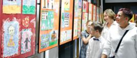 Uczniowie i nauczyciele oglądają wystawę rysunków.