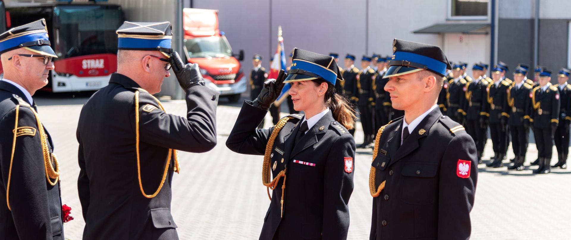 Zastępca komendanta głównego PSP salutuje do wyróżnionej kobiety oficer.