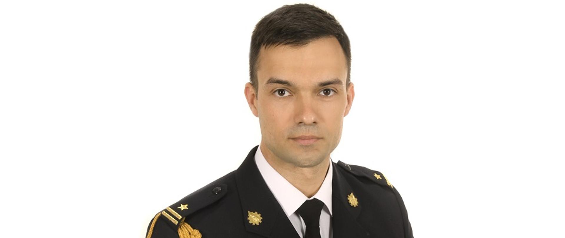 Zdjęcie portretowe zastępcy komendanta mł. bryg. Krystiana Masalskiego na jasnym tle w mundurze galowym