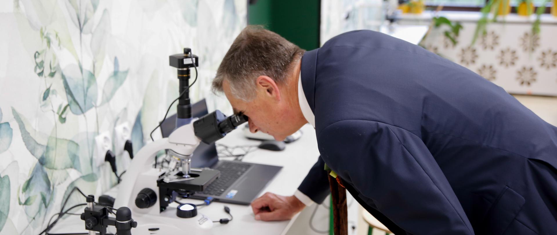 Wojewoda lubelski patrzy przez mikroskop.