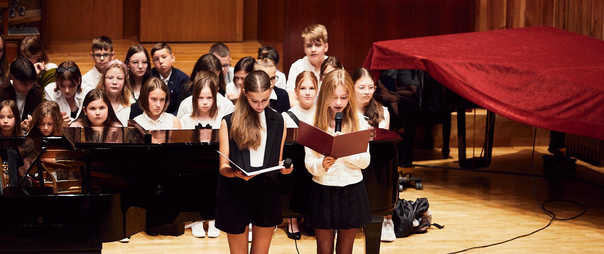 Na zdjęciu uczniowie pierwszych klas, stoją w rzędzie. w tle fortepian