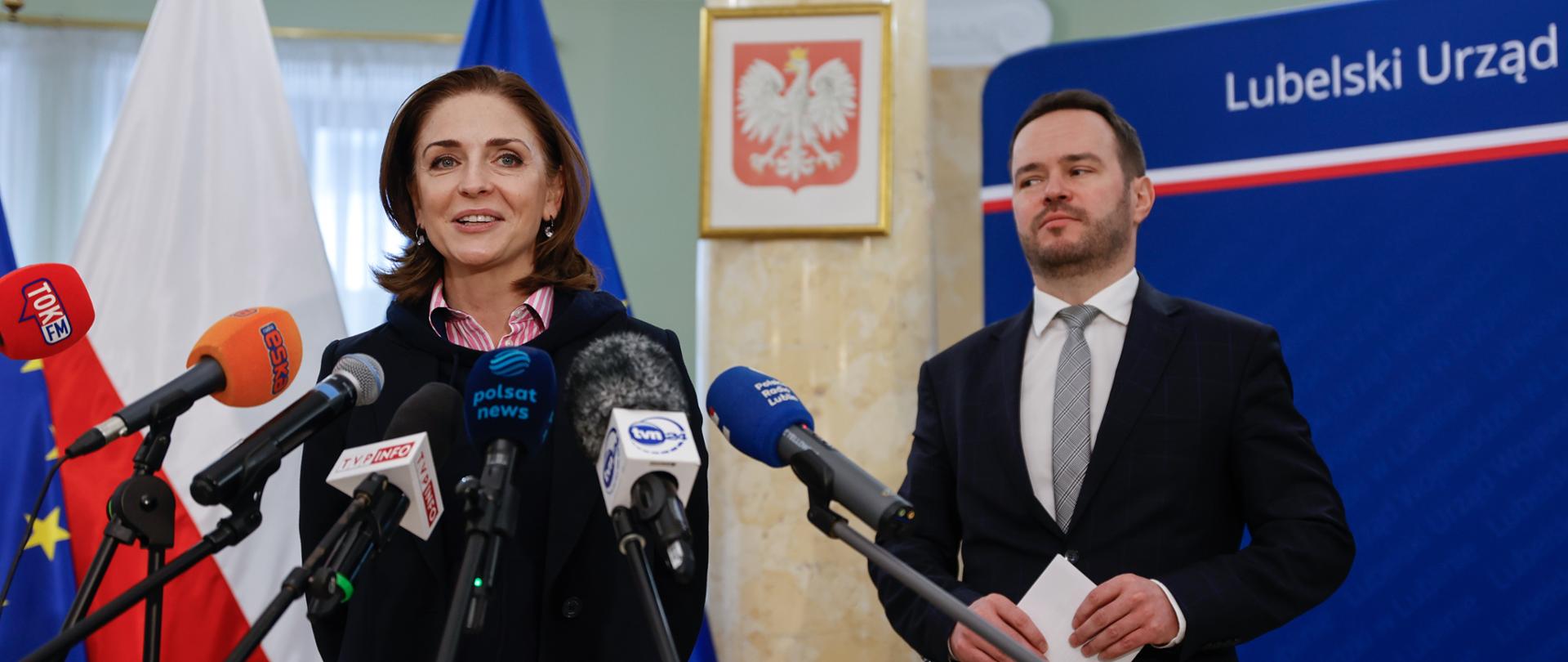 Wiceministra edukacji narodowej Joanna Mucha i wojewoda lubelski Krzysztof Komorski podczas konferencji prasowej stoją przed mikrofonami. 