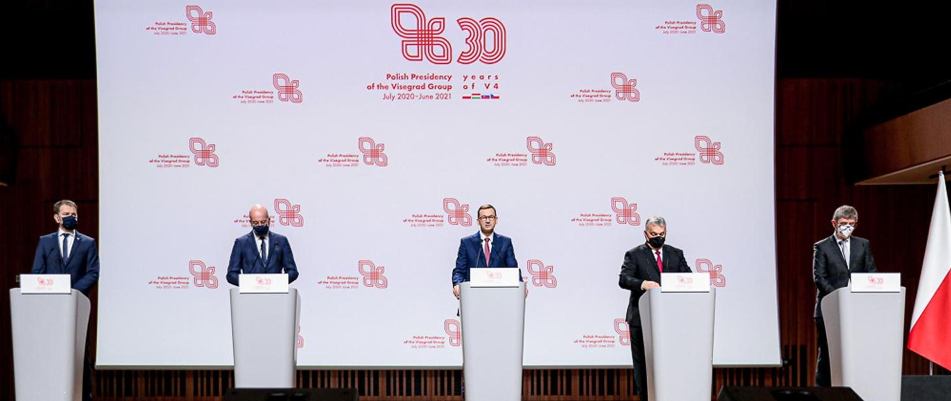 Premierzy Polski, Czech, Węgier, Słowacji oraz szef Rady Europejskiej w trakcie konferencji - stoją przy mównicach.