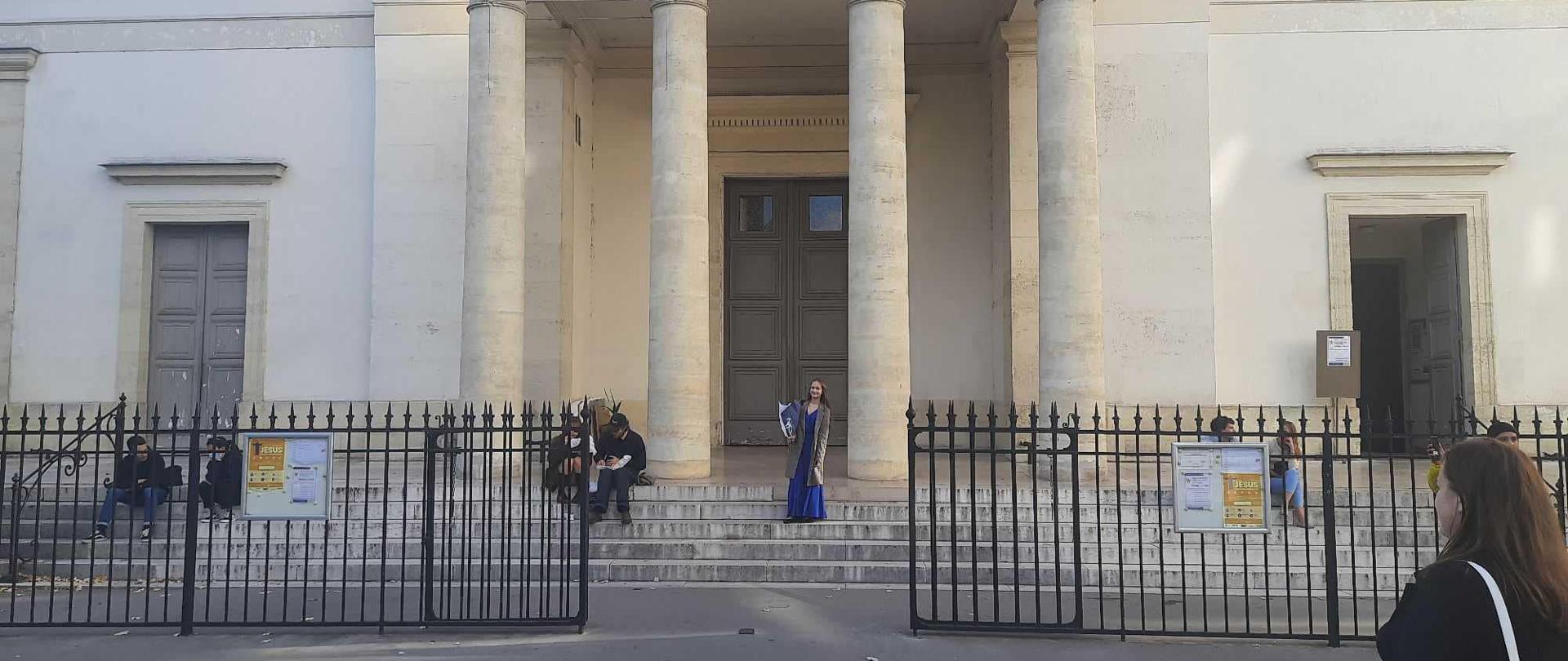 Antonina stoi na schodach przed kościołem w wieczorowej sukni.