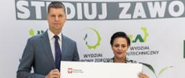 Minister Piontkowski i kobieta trzymają w rękach duży symboliczny czek z napisem 3 903 600 zł.