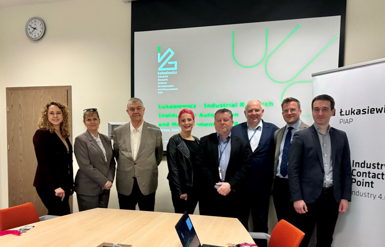 Zdjęcie zbiorowe, pod ścianą stoi kilka osób.