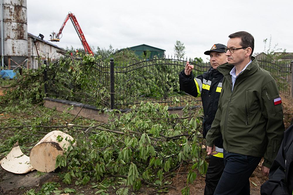 Premier Mateusz Morawiecki idzie wśród połamanych drzew.