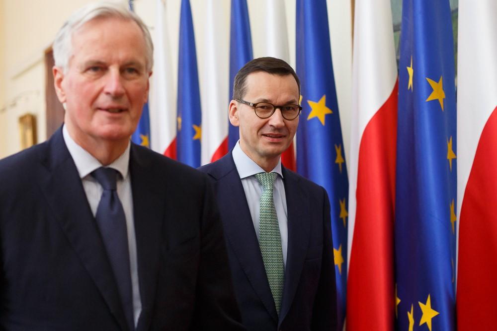 Premier Mateusz Morawiecki i Michel Barnier na tle flag.