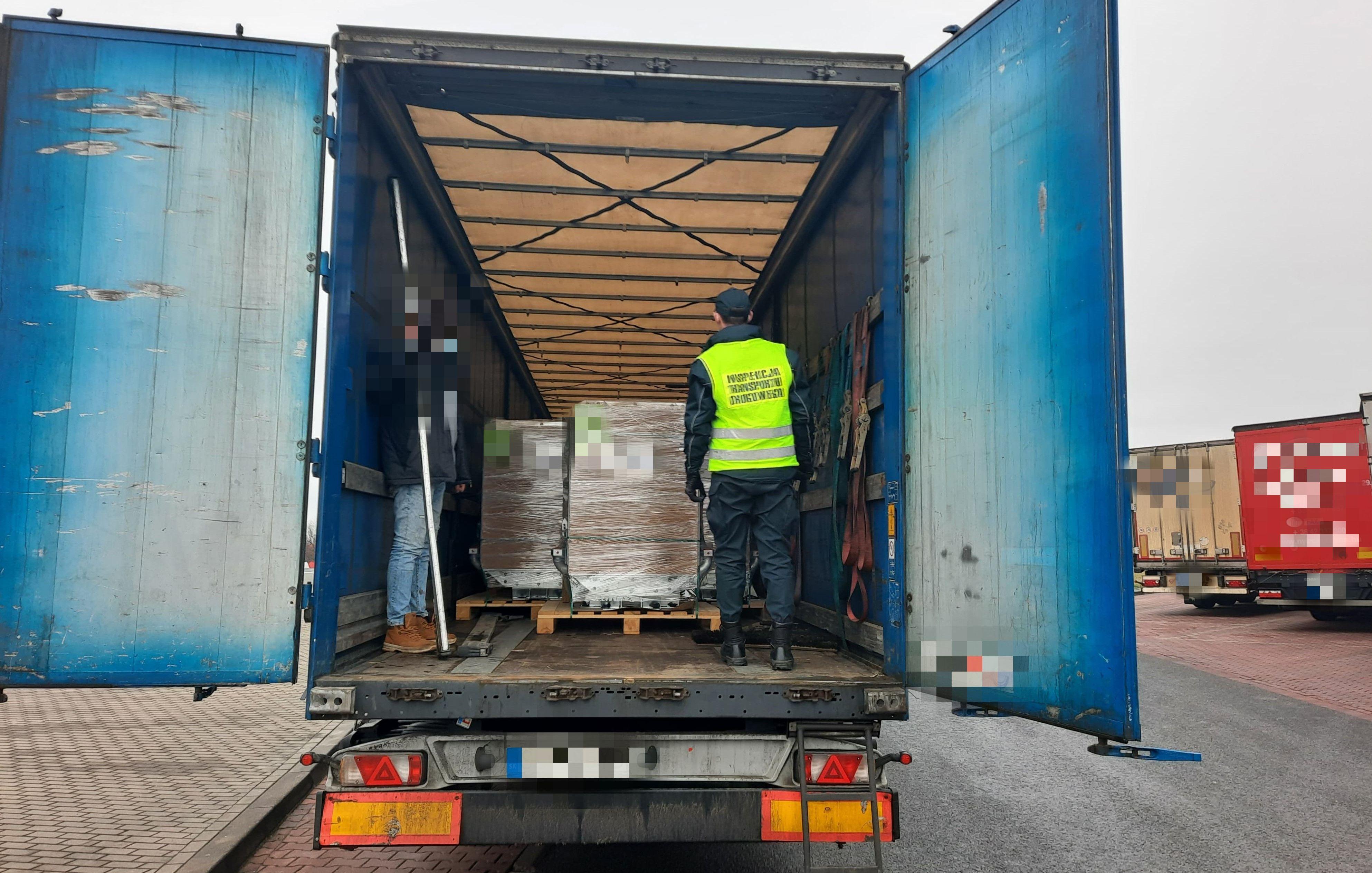 Inspektor kontroluje zawartość naczepy ciężarowej.