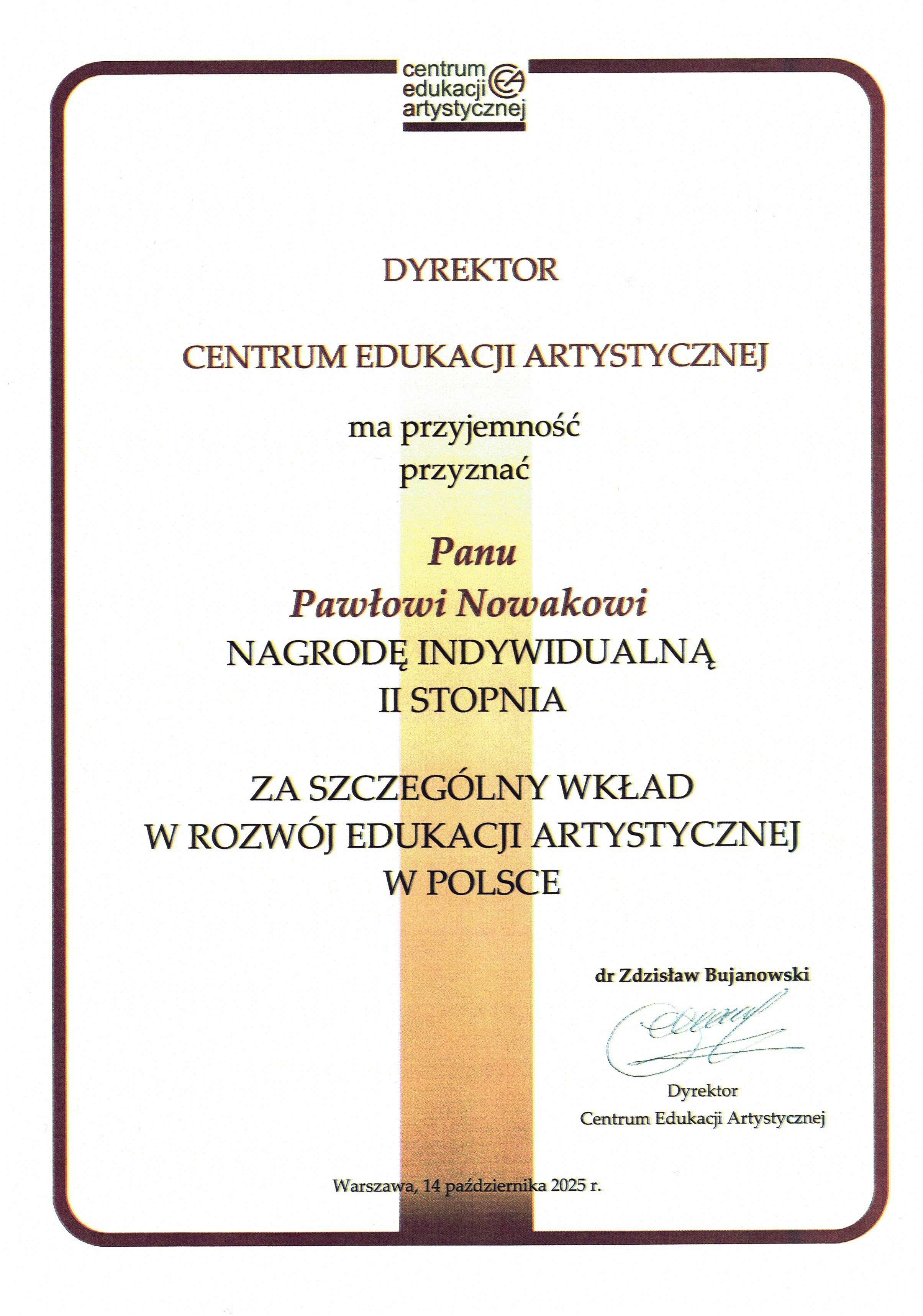 Kadr przedstawia zbliżenie na pionowy dyplom, obramowany brązową linią z zaokrąglonymi rogami, na jasnym tle. Na górze, pośrodku znajduje się logo z tekstem "centrum edukacji artystycznej". Pod nim jest centralnie wyjustowany tekst, który brzmi: DYREKTOR CENTRUM EDUKACJI ARTYSTYCZNEJ ma przyjemność przyznać Pani/Panu Pawłowi Nowakowi NAGRODĘ INDYWIDUALNĄ II STOPNIA ZA SZCZEGÓLNY WKŁAD W ROZWÓJ EDUKACJI ARTYSTYCZNEJ W POLSCE Poniżej tekstu, po prawej stronie, znajduje się: dr Zdzisław Bujanowski (podpis) Dyrektor Centrum Edukacji Artystycznej Na dole, pośrodku, znajduje się tekst: Warszawa, 14 października 2025 r. Przez środek dyplomu, za niektórymi słowami, biegnie pionowy, szeroki pasek w kolorach od jasnego beżu do brązu.