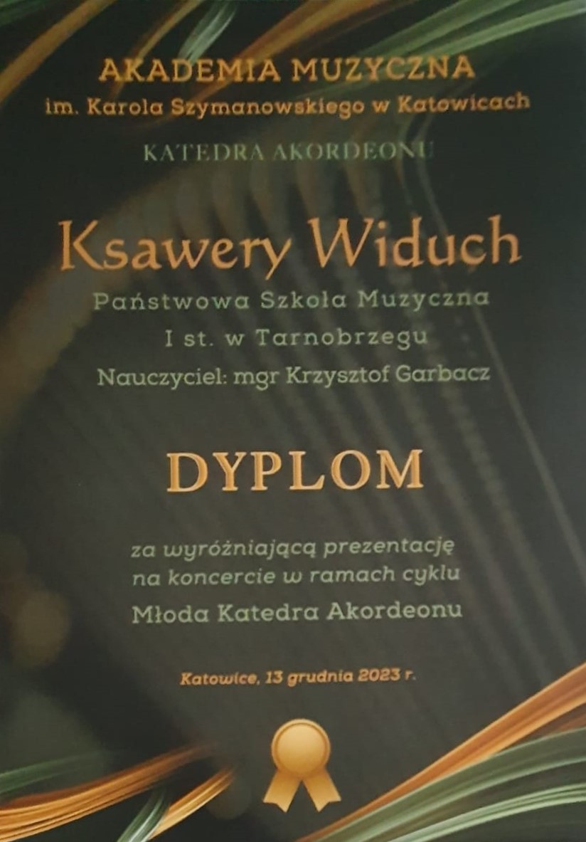 Dyplom Ksawerego Widucha za wyróżniającą prezentację na koncercie w ramach cyklu Młoda Katedra Akordeonu. Całość na ciemnym tle zdobiona pomarańczowo-zielonymi wstęgami. Napisy w kolorze zielono-pomarańczowym. Na dole grafika przedstawiająca kotylion w kolorze pomarańczowym.