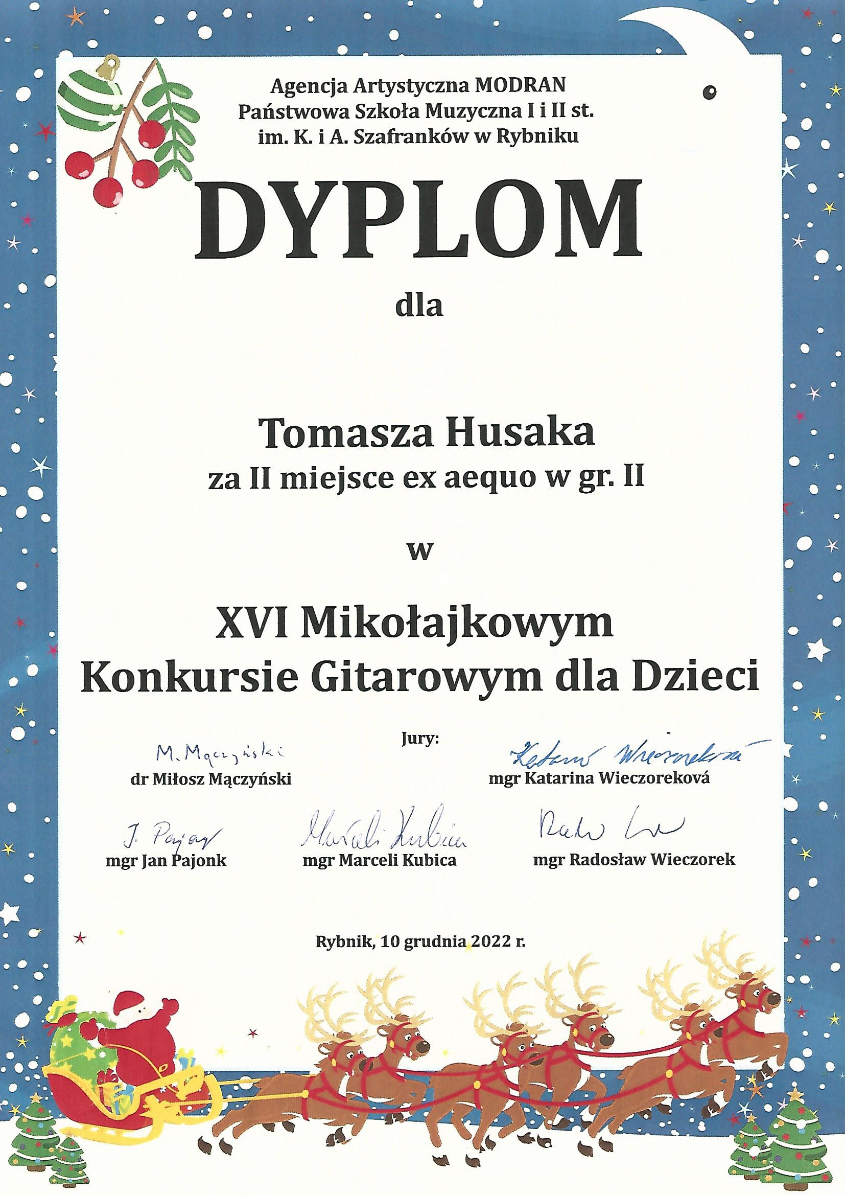 Grafika - dyplom. Tło białe, jedynie obramowanie w kolorze ciemnoniebieskim - z elementami graficznymi przedstawiającymi zimę (gwiazdki, płatki śniegu) oraz okres świąteczny - ubrane choinki i sanie świętego Mikołaja z zaprzęgiem reniferów. Na górze napis Agencja Artystyczna MODRAN, Państwowa Szkoła Muzyczna I i II stopnia im. K. i A. Szafranków w Rybniku. Poniżej duży napis DYPLOM, a jeszcze niżej kolejne napisy - dla Tomasz Husaka za zajęcie II miejsca ex aequo e grupie II w XVI Mikołajkowym Konkursie Gitarowym dla dzieci. Na samym dole imiona i nazwiska Jurorów wraz z ich podpisami. oraz miejscowość i data - Rybnik, 10 grudnia 2022 roku.