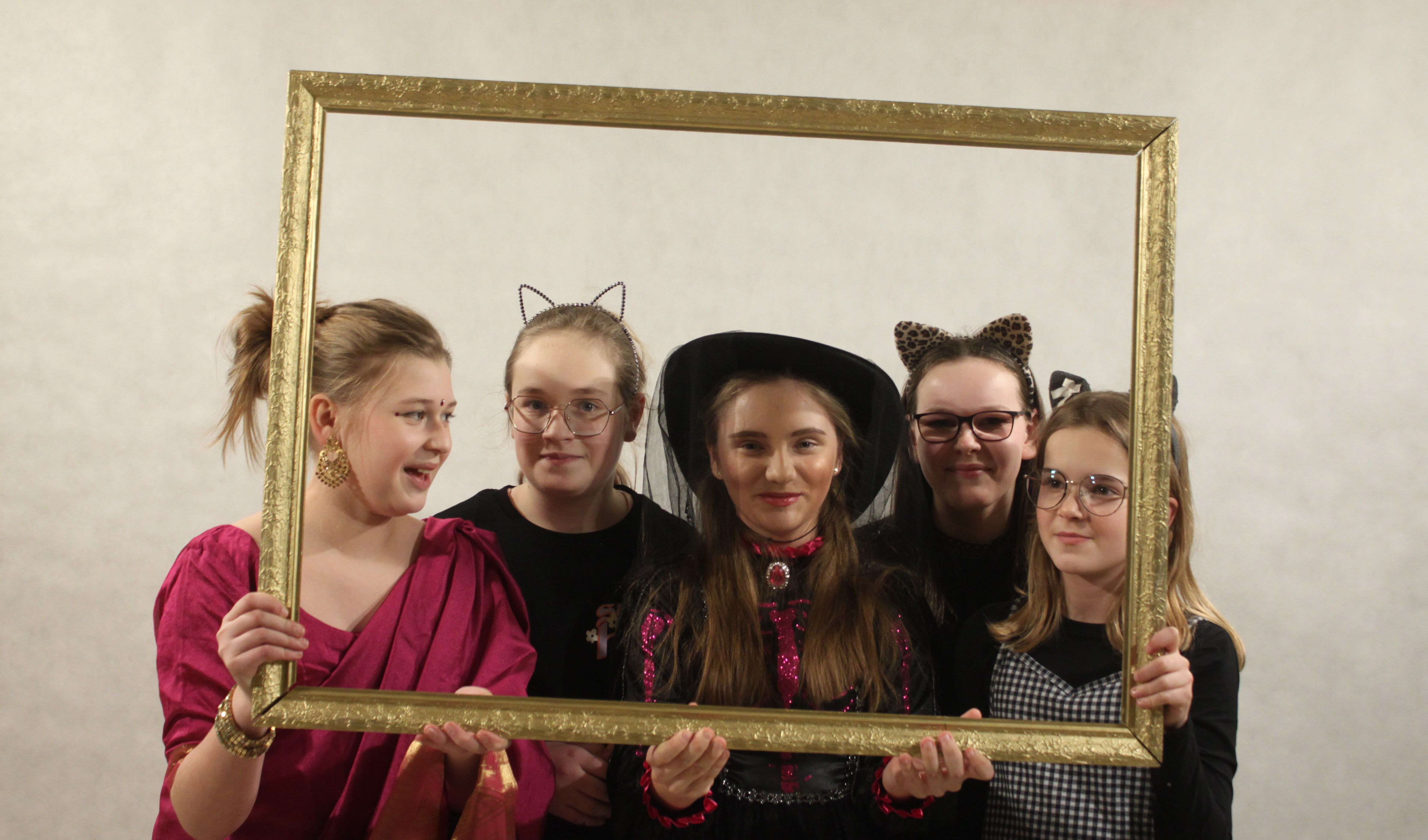 Zdjęcie. Zabawa karnawałowa - zdjęcie pamiątkowe uczestników zabawy. Pięć młodych dziewcząt pozuje do zdjęcia w pustej ramce do obrazu.