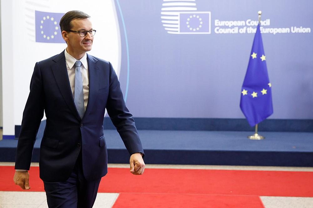 Premier Mateusz Morawiecki na tle flagi Unii Europejskiej.