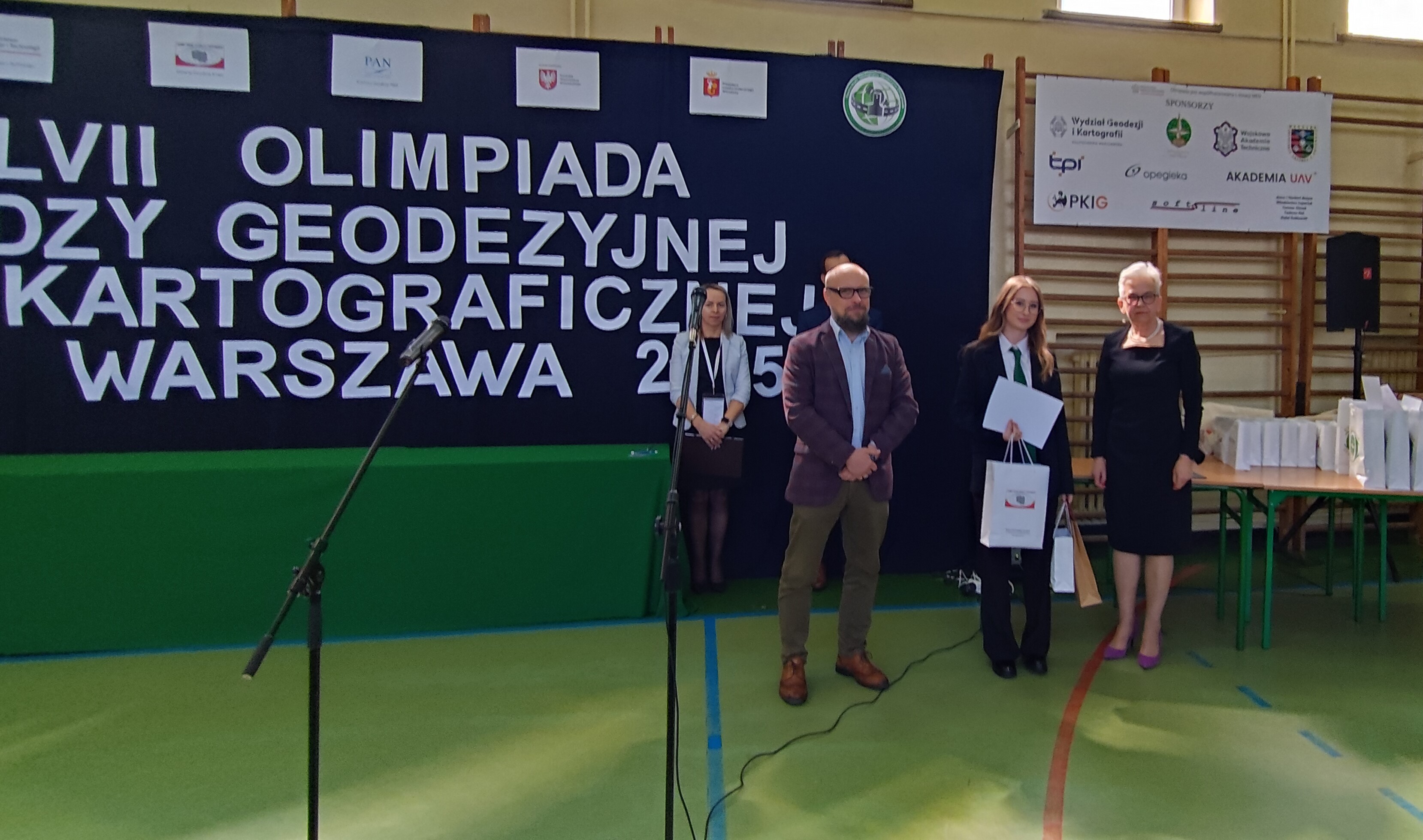 Zdjęcie przedstawia wręczenie nagrody ufundowanej przez Głównego Geodetę Kraju jednemu z laureatów olimpiady 