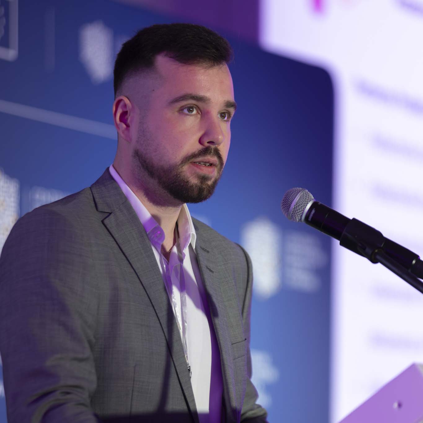 Przy mównicy stoi Pan Michał Mucha. Wzrok kieruje w stronę uczestników konferencji. Mówi do mikrofonu.