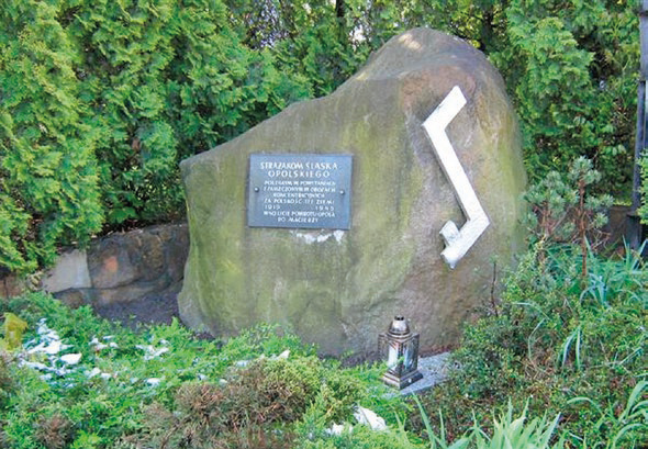 Zdjęcie przedstawia obelisk znajdujący się przed Komendą Wojewódzką PSP w Opolu.