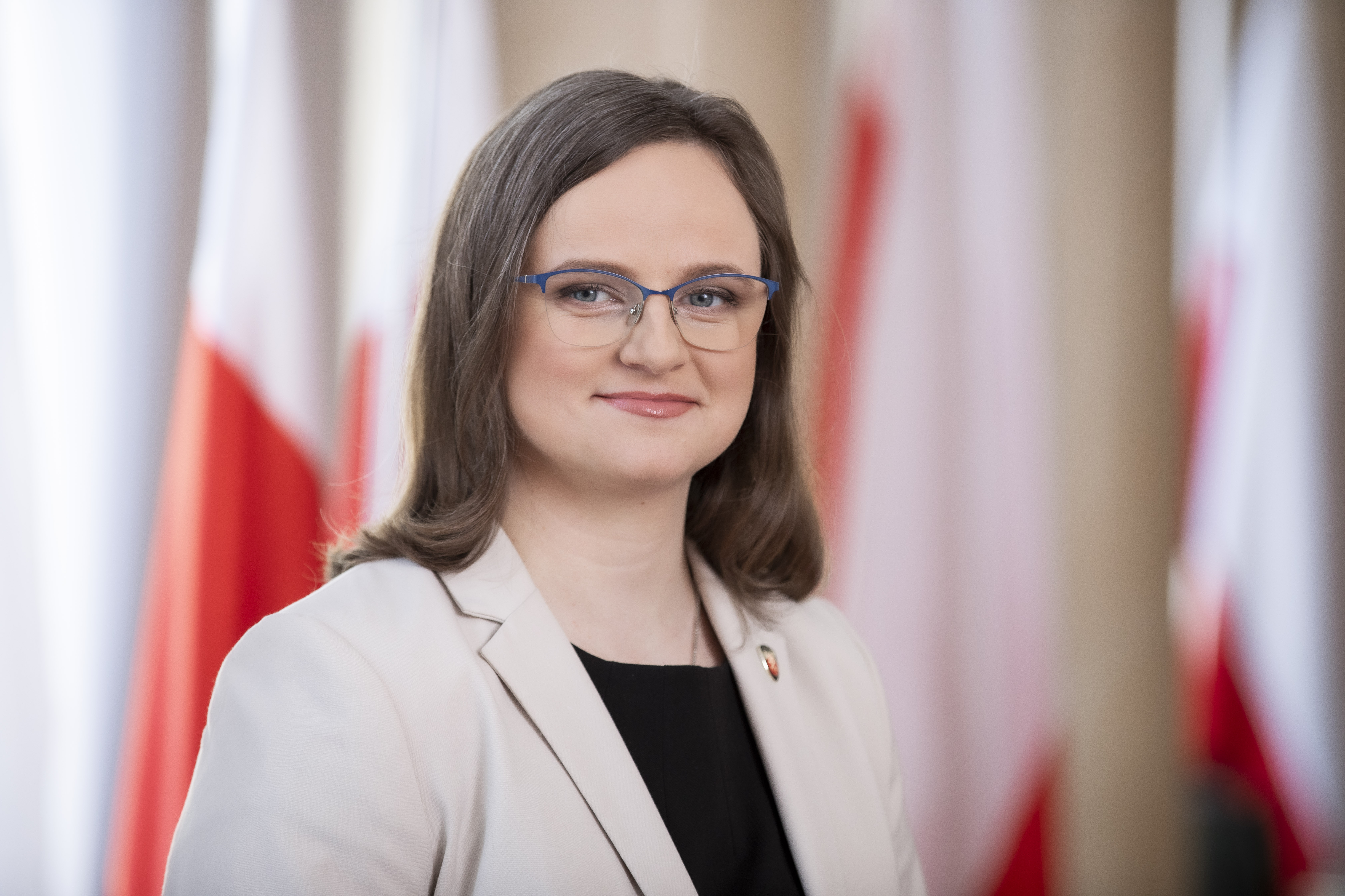 Anna Chałupa Podsekretarz Stanu, Zastępca Szefa Krajowej Administracji Skarbowej na tle flag