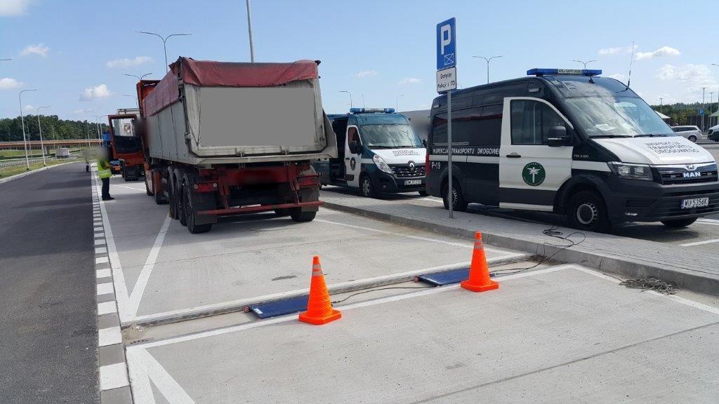 Zestaw stojący za rozłożonymi wagami i zaparkowane obok niego radiowozy ITD.