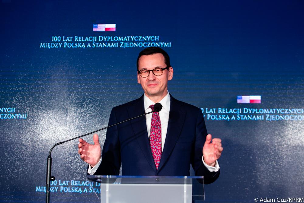 Premier Mateusz Morawiecki stoi przy mównicy.