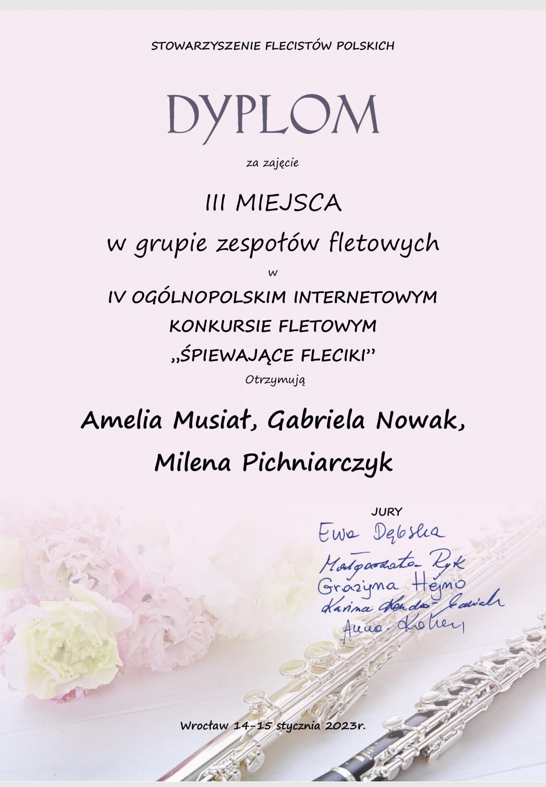 Dyplom na różanym tle, w dole dyplomu pąki kwiatów oraz dwa flety. Treść dyplomu: Stowarzyszenie flecistów polskich, Dyplom za zajęcie trzeciego miejsca w grupie zespołów fletowych w IV Ogólnopolskim Internetowym Konkursie Fletowym Śpiewające Fleciki otrzymują Amelia Musiał, Gabriela Nowak, Milena Pichniarczyk. Poniżej podpisy jury. Na samym dole Wrocław oraz data 14-15 stycznia 2023 r. 