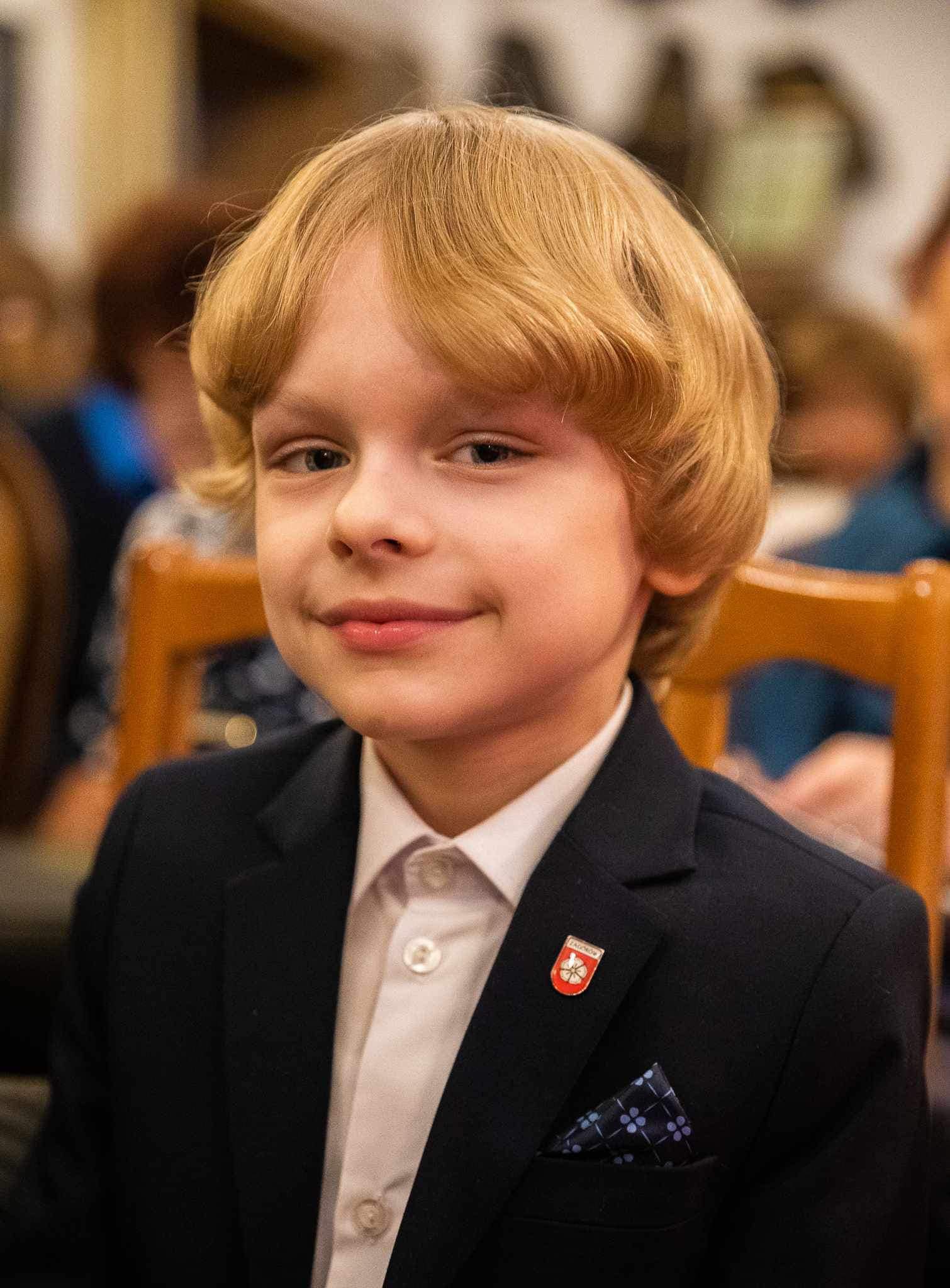 chłopiec w garniturze siedzący na krześle