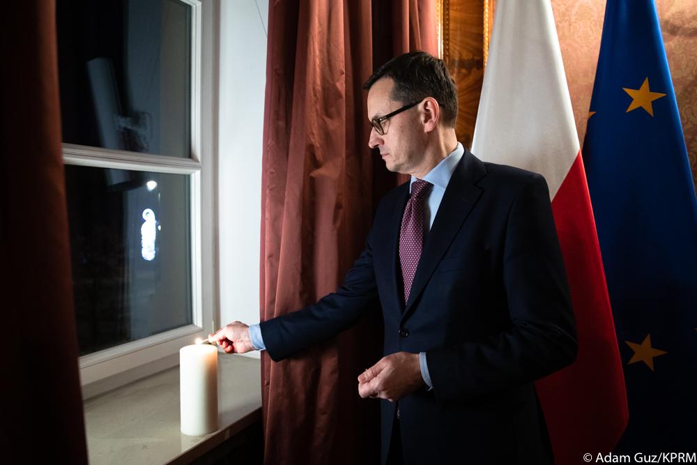 Premier Mateusz Morawiecki zapala świecę.