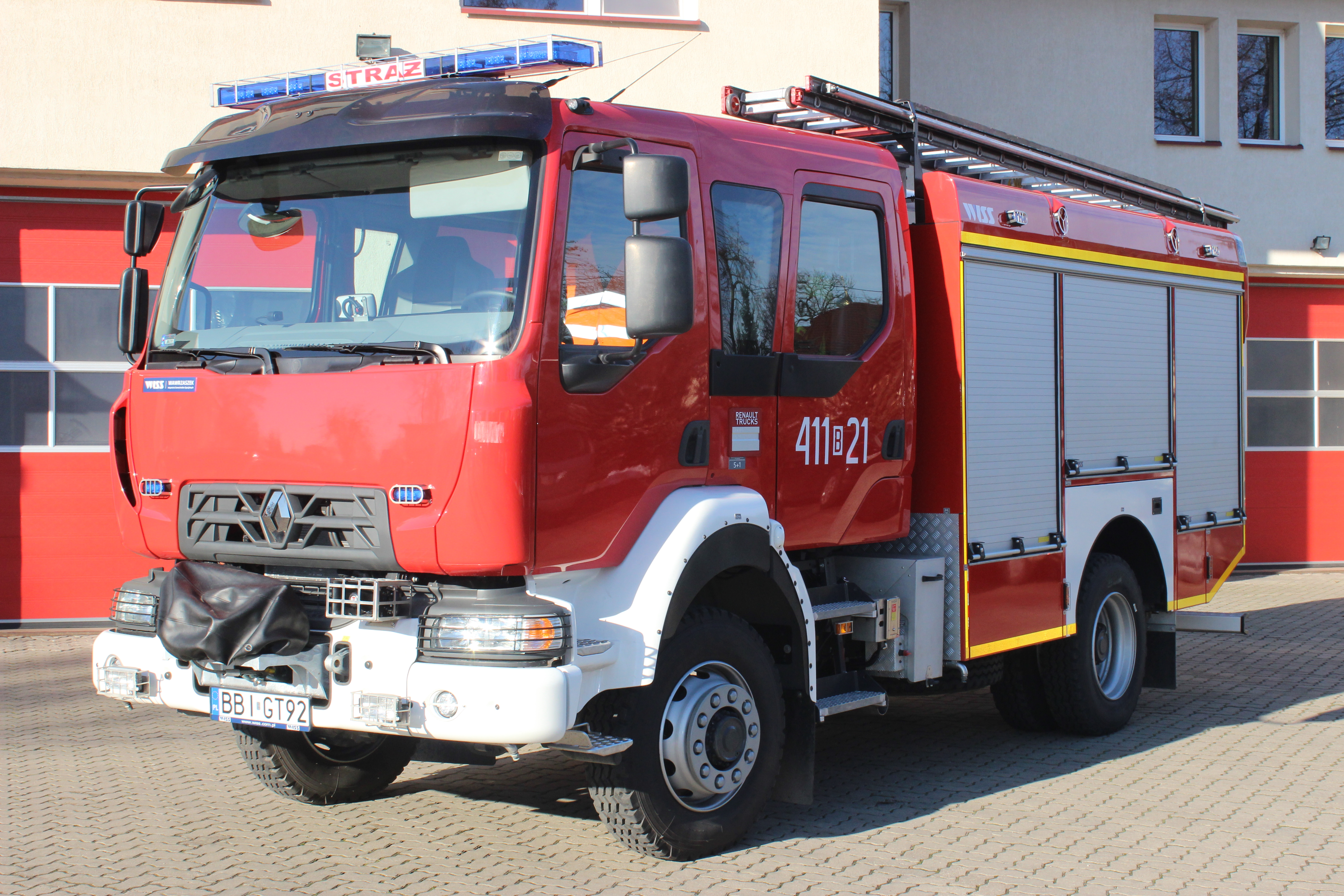 Zdjęcie przedstawia średni samochód gaśniczy na podwoziu RENAULT D14 stojący na tle strażnicy.