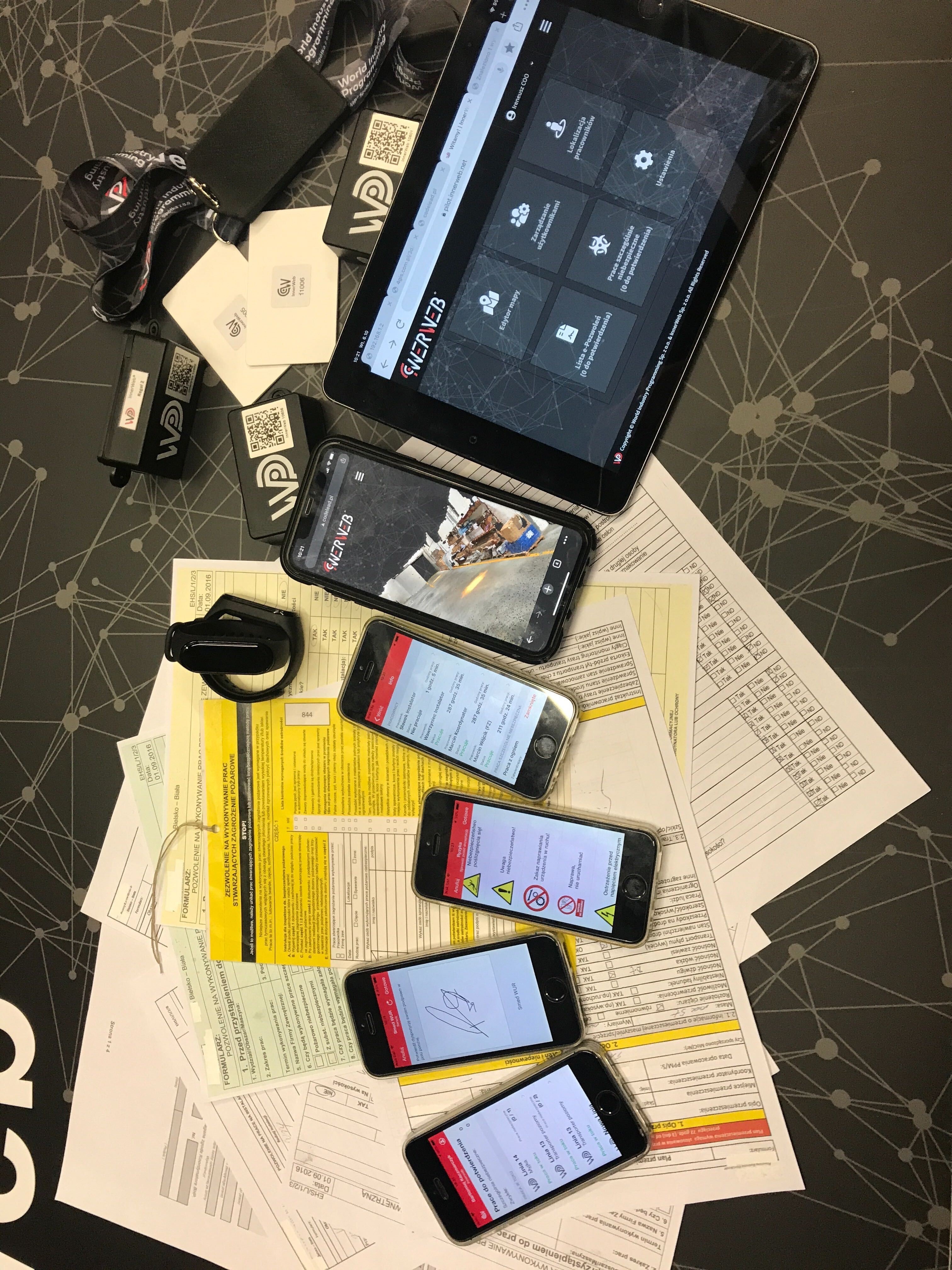 Na stole z dokumentami leżą urządzenia mobilne prezentujące aplikację InnerWeb