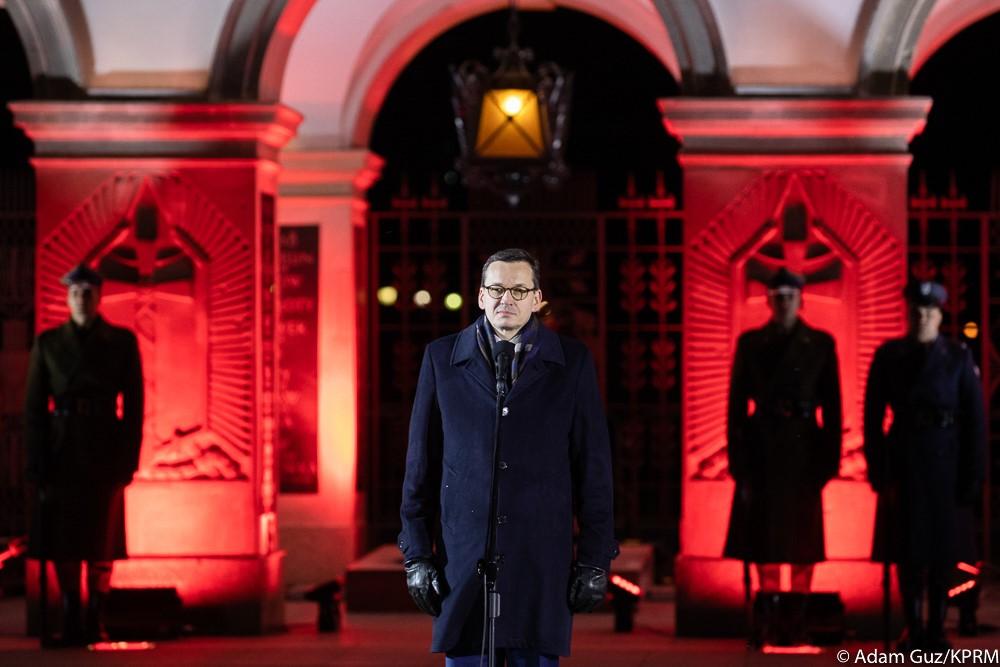 Premier Mateusz Morawiecki przemawia przed mikrofonem, w tle Grób Nieznanego Żołnierza.