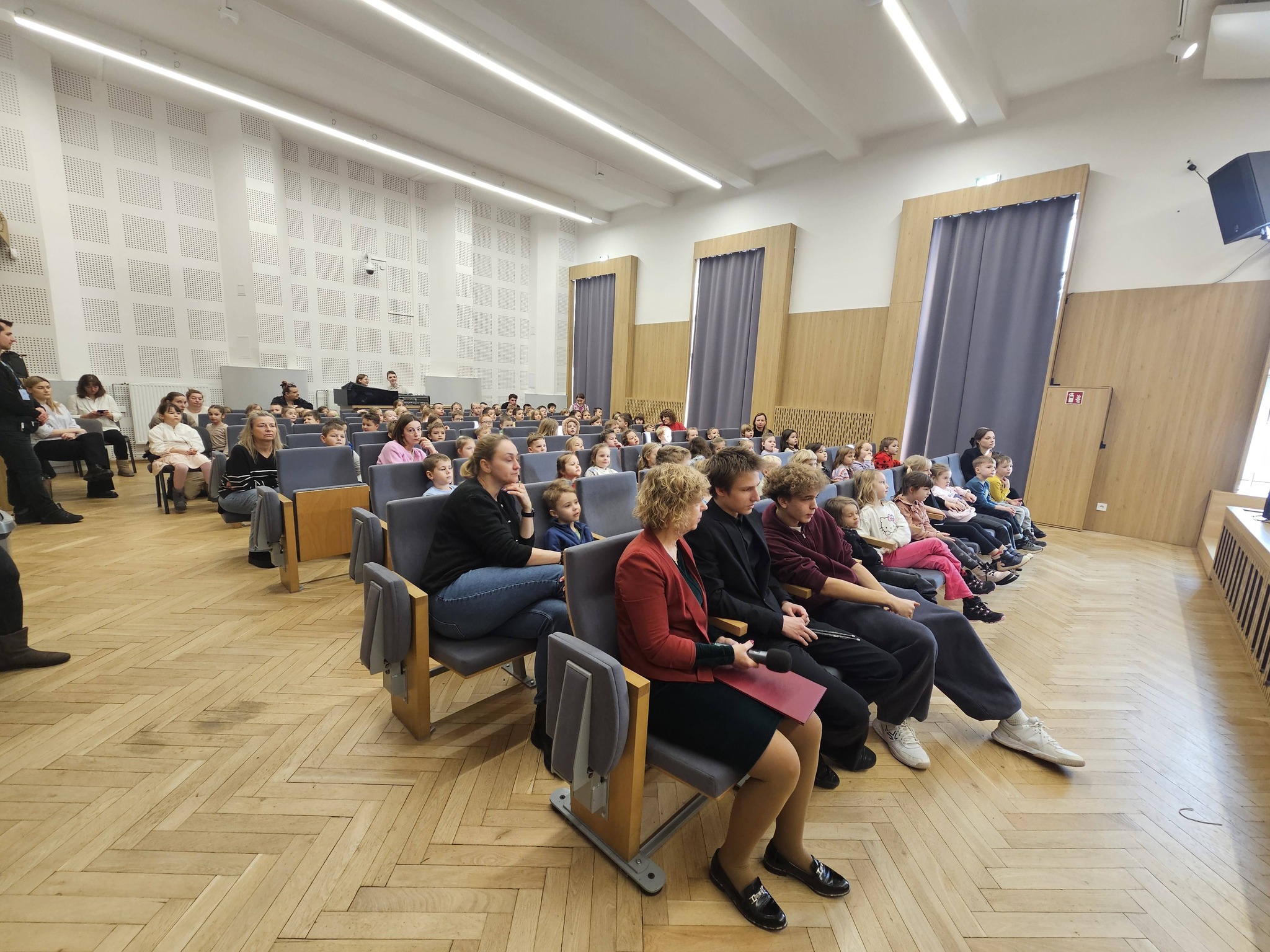 Widok sali koncertowej szkoły z publicznością - przedszkolakami.