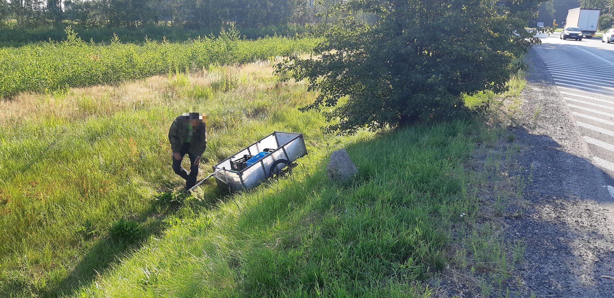 W rowie leży przyczepka. Obok pochyla się mężczyzna. 