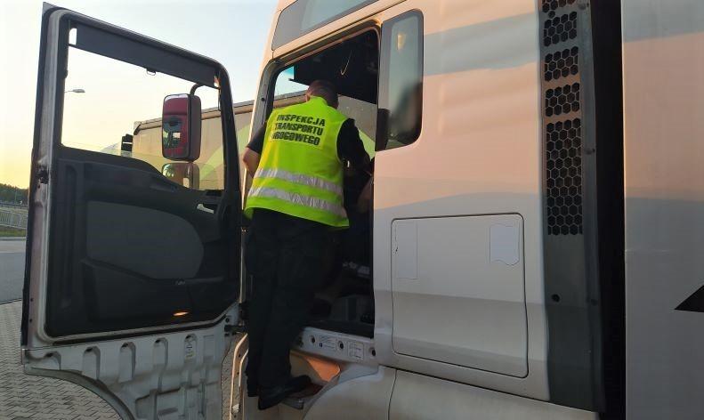 Inspektor kujawsko-pomorskiej ITD wchodzi do kabiny kontrolowanego samochodu ciężarowego.