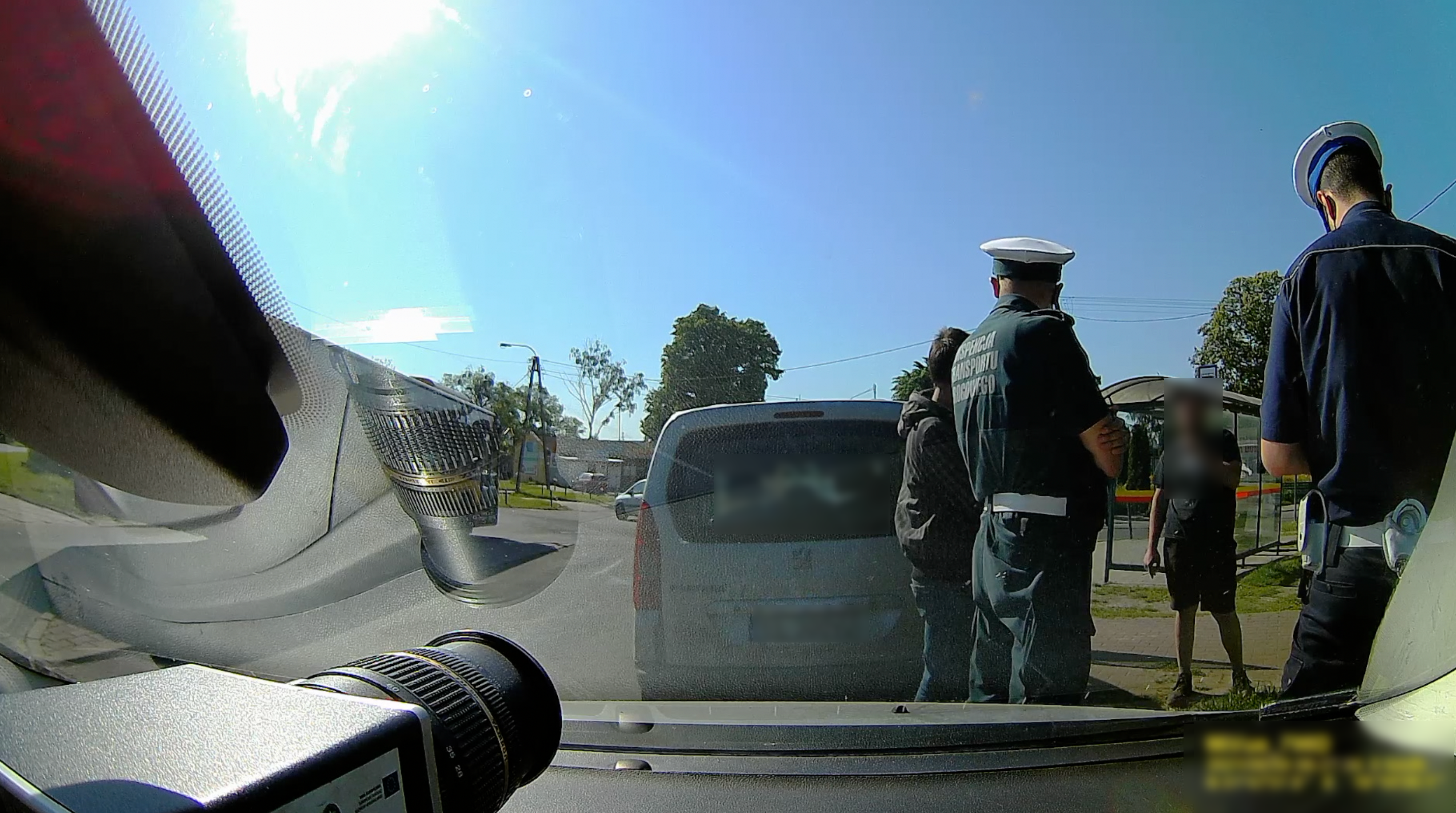 Inspektor oraz policjant prowadzą czynności kontrolne z kierowcą