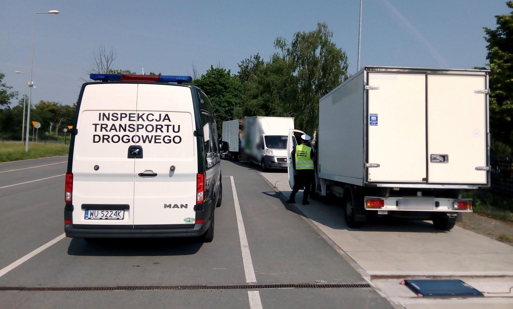Radiowóz ITD i inspektor stojący obok kontrolowanego samochodu dostawczego.
