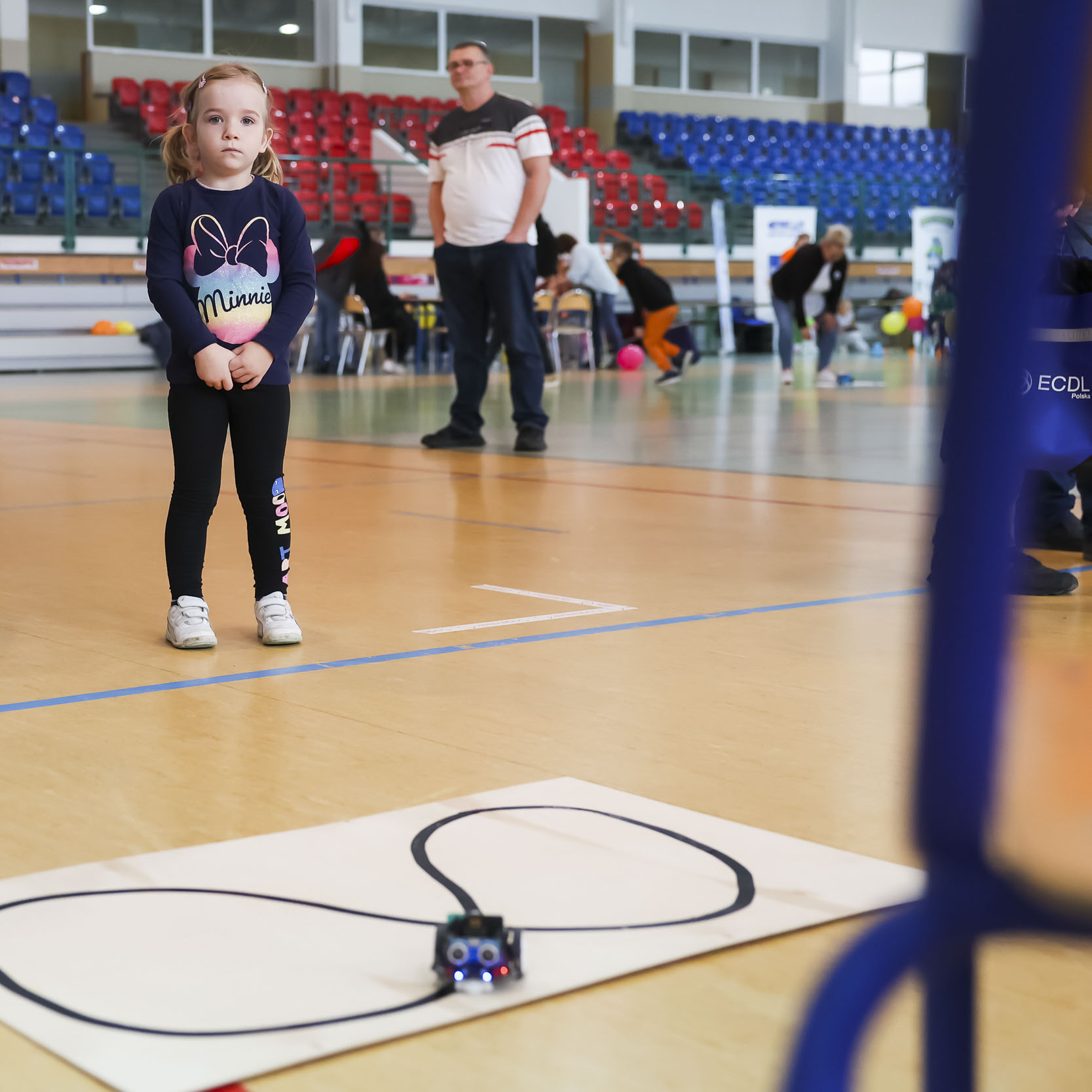 Dziewczynka na Sali gimnastycznej przyglądająca się robotowi na torze
