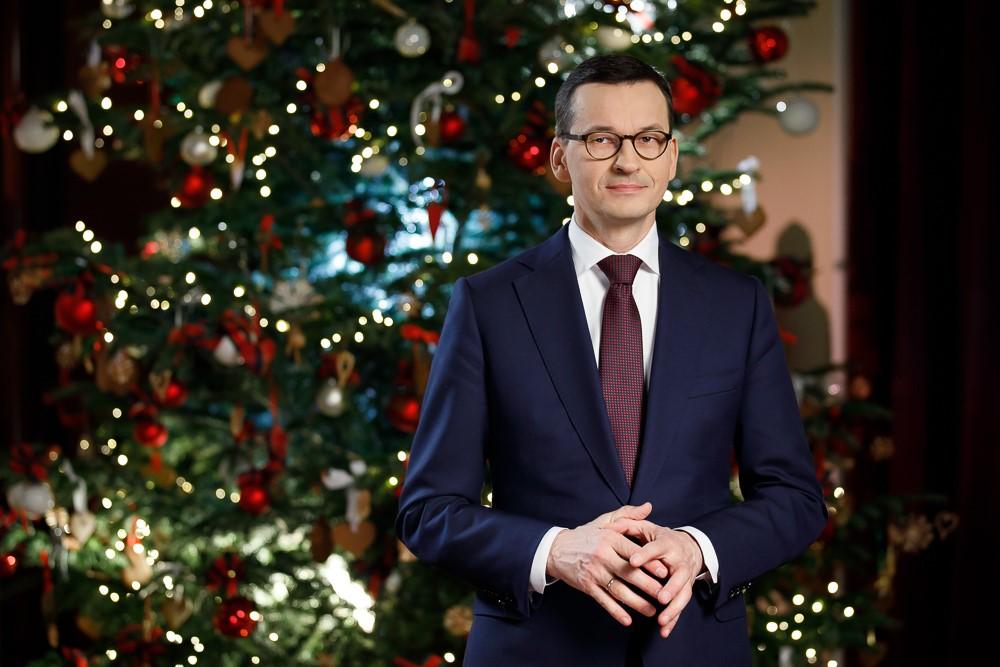 Premier Mateusz Morawiecki, a w tle świąteczna choinka.