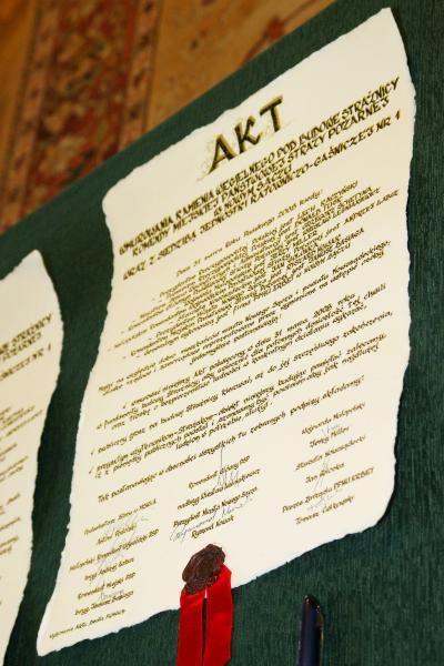 Widok aktu wmurowania kamienia węgielnego z pieczęcią i podpisami. Akt wykonany na ozdobnym papierze a pismo odręczne.