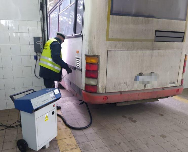 Inspektor stoi obok autobusu w trakcie badania składu spalin dymomierzem