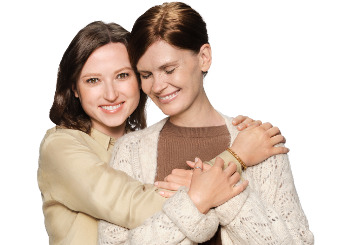 13.1.Zdjęcie: Dwie kobiety, 35-letnia córka i 55-letnia matka, obejmują się z czułością, stoją przodem. Córka patrzy na wprost i uśmiecha się szeroko. Matka ma zamknięte oczy i uśmiecha się.