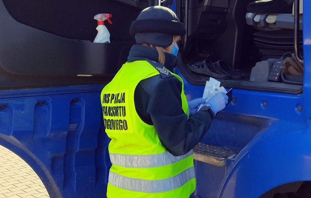 Inspektor kontroluje zapisy na wydrukach z tachografu ciężarówki.